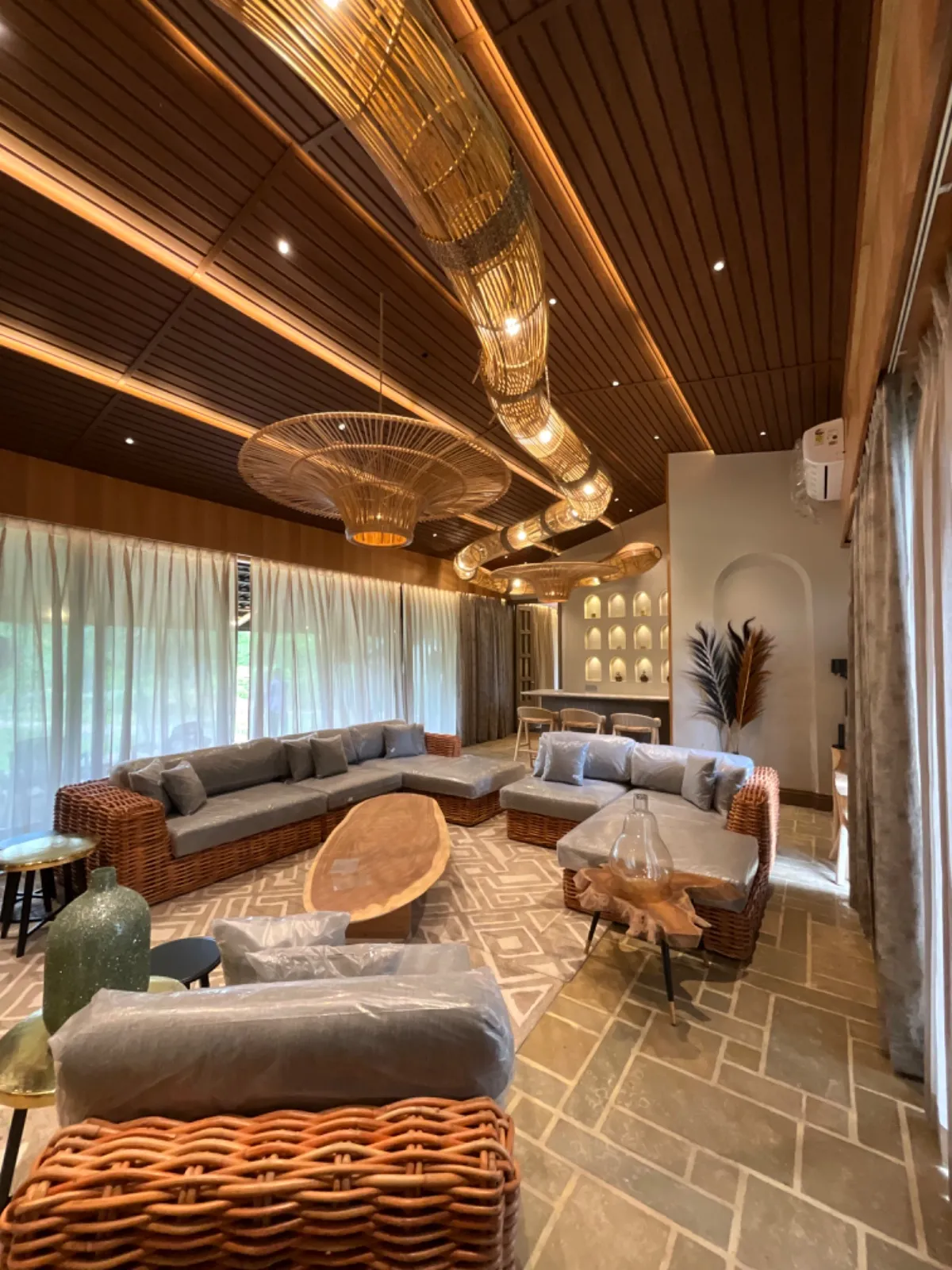 Double-height living room of the Koregaon Park penthouse with floor-to-ceiling windows overlooking the tree canopy